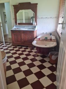 a bathroom with a tub and a mirror and a checkered floor at Birchwood Gardens Bed and Breakfast in Narrikup +45 photos
