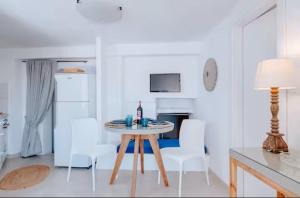 a white kitchen with a table and white chairs at Casa View in Akrotiri