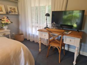 a bedroom with a desk with a television on it at Birchwood Gardens Bed and Breakfast in Narrikup