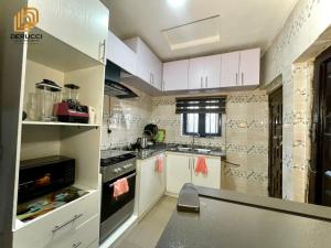 a kitchen with white cabinets and a stove top oven at Derucci Luxury Apartment in Owerri