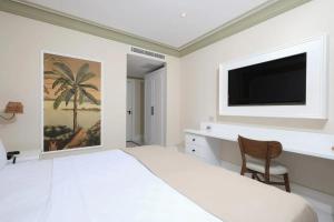 a white bedroom with a large bed and a flat screen tv at DBD Hotel Çeşme in Yumru
