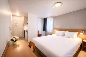 a bedroom with a large white bed and a table at Séjours & Affaires Bordeaux de L'Yser in Bordeaux