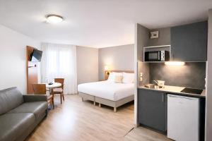 a hotel room with a bed and a kitchen and a couch at Séjours & Affaires Bordeaux de L'Yser in Bordeaux