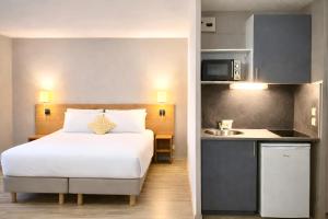 a hotel room with a bed and a kitchen at Séjours & Affaires Bordeaux de L'Yser in Bordeaux +7 photos
