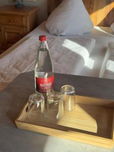 a bottle and two glasses on a tray on a bed at Pension Bergseeblick in Titisee-Neustadt