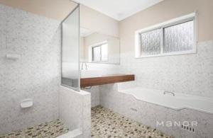 a bathroom with a tub and a sink and a mirror at Room 44 in Baulkham Hills