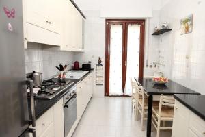 a kitchen with white cabinets and black counter tops at VicoStay di Casa Stella in Vico Equense