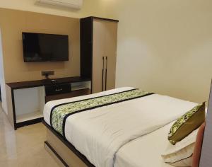 a bedroom with a bed and a flat screen tv at Hotel Gurudev Inn in Junnar