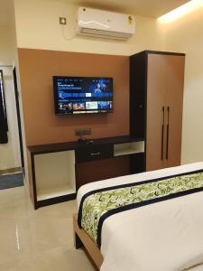 a bedroom with a tv on the wall and a bed at Hotel Gurudev Inn in Junnar +16 photos