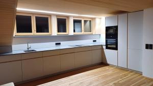 a kitchen with white cabinets and a black appliances at GebirgsImker-Apartment in Egg +6 photos