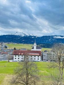 a large white building in a field with snow covered mountains at GebirgsImker-Apartment in Egg