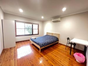a bedroom with a bed and a desk and a window at Room 00 in Baulkham Hills