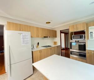 a kitchen with a white refrigerator and wooden cabinets at Room 00 in Baulkham Hills
