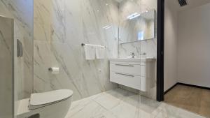 a white bathroom with a toilet and a sink at Azure Coast Deluxe Residence - Budva Seafront Living Suites in Bečići +46 photos