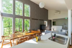 a kitchen and living room with a wooden table and some windows at 翠葉 Rusutsu in Rusutsu