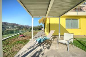 a patio with two chairs and a yellow house at Iris - Costadoro Holiday Home in Imperia +7 photos