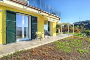 a yellow house with a patio with a table and chairs at Iris - Costadoro Holiday Home in Imperia