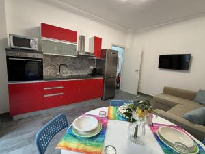a living room with a table and a kitchen with red cabinets at Arcobaleno in Turin