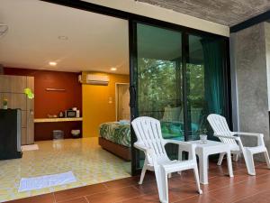 a living room with two white chairs and a table at Khaolak Nature House in Khao Lak