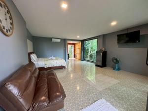 a living room with a leather couch and a clock at Khaolak Nature House in Khao Lak