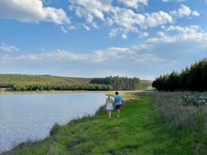 a man and woman standing next to a body of water at Shiloh Lodges Tweefontein in Mooiriver