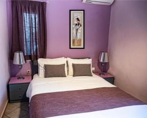a bedroom with purple walls and a bed with two lamps at Sand Garden Apart, Easy Stay by Heraklion Coast in Ayía Marína