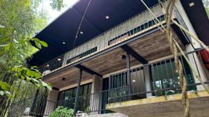 a building with a black roof and a balcony at Khaolak Nature House in Khao Lak