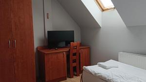 a bedroom with a tv on a wooden cabinet with a bed at Hostel RAV in Tomaszów Mazowiecki