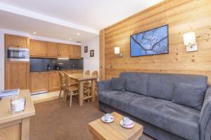 a living room with a couch and a kitchen at Résidence Les Chalets du Forum - Courchevel 1850 in Courchevel
