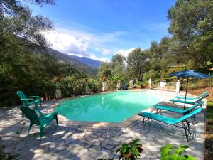 a swimming pool with two chairs and an umbrella at La licorne in Serriera