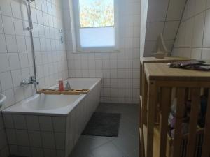 a white bathroom with a tub and a sink at Ruhige Ferienwohnung NB in Neubrandenburg +4 photos