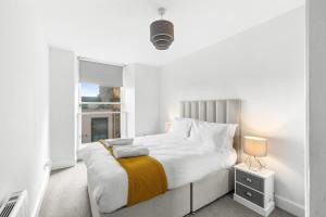 a white bedroom with a large bed and a window at Henry's Apartment on Commercial Street in Dundee
