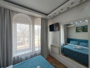 a bedroom with a blue bed and a large window at Bella Donna Hotel in Chişinău