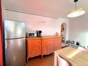 a kitchen with a stainless steel refrigerator and a table at Hotel L'Astrolabe in Oloron-Sainte-Marie