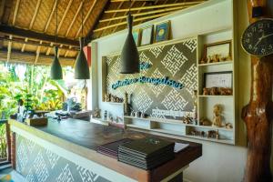 a restaurant with a counter and a clock on the wall at The Calmtree Bungalows in Canggu