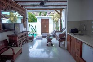 a kitchen with a living room with a couch and a tv at The Calmtree Bungalows in Canggu