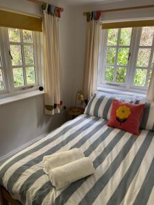a bedroom with a striped bed with two windows at The lodge in Bodmin