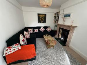 a living room with a black couch and a fireplace at The lodge in Bodmin