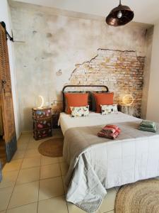 a bedroom with a bed and a brick wall at LA FONTAINE AU LOUP in Saint-Maurice-sur-Eygues