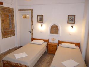 two twin beds in a room with a window at Vasilis Ios Place II in Ios Chora