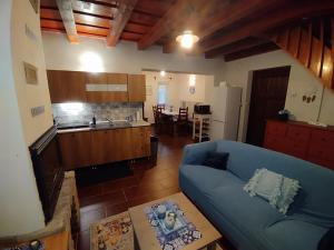 a living room with a blue couch and a kitchen at Kiscsengőd Vendégház in Csengőd