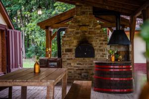a patio with a brick oven and a wooden table at Kiscsengőd Vendégház in Csengőd