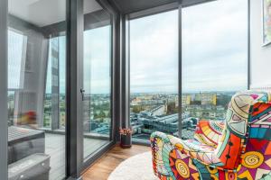 a living room with a chair and large windows at Hanza Signature Sky in Szczecin