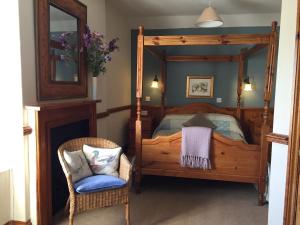 a bedroom with a wooden bed and a chair at The Bull Inn West Tanfield in Ripon