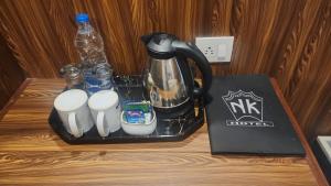 a black tea kettle and cups on a table at HOTEL N K RESIDENCY in Guwahati