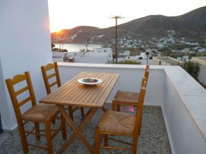 a wooden table and chairs on a balcony with a view at Vasilis Ios Place II in Ios Chora