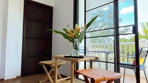 a table with a vase of flowers on it next to a window at Similan Home Stay in Ban Lam Ru (1)