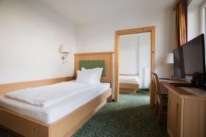 a bedroom with a bed and a desk and a television at Garni Kleefeld in Schenna +23 photos