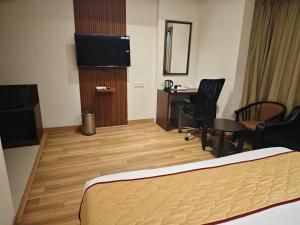 a hotel room with a bed and a desk and a television at Esthell Hotel in Chennai