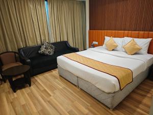 a hotel room with a bed and a chair at Esthell Hotel in Chennai